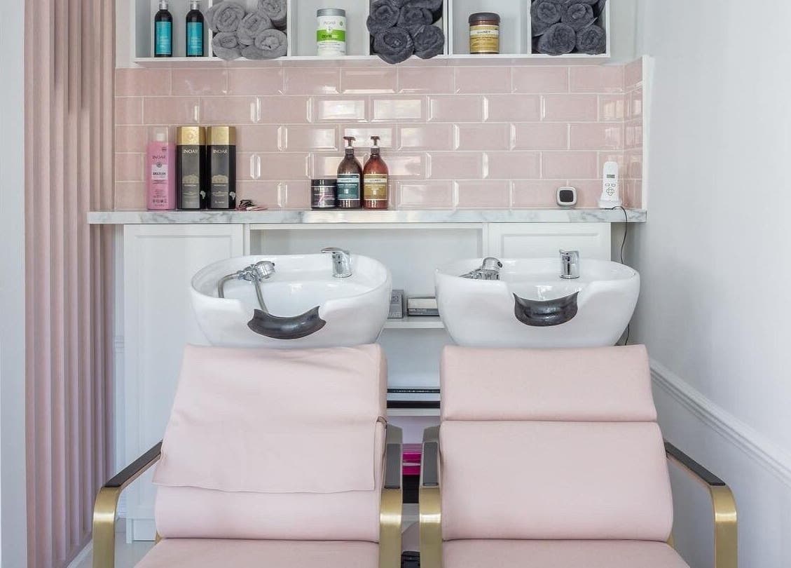 Luxurious wash station at The Dolls London SW3, London, England, GB with pink chairs and beauty products.