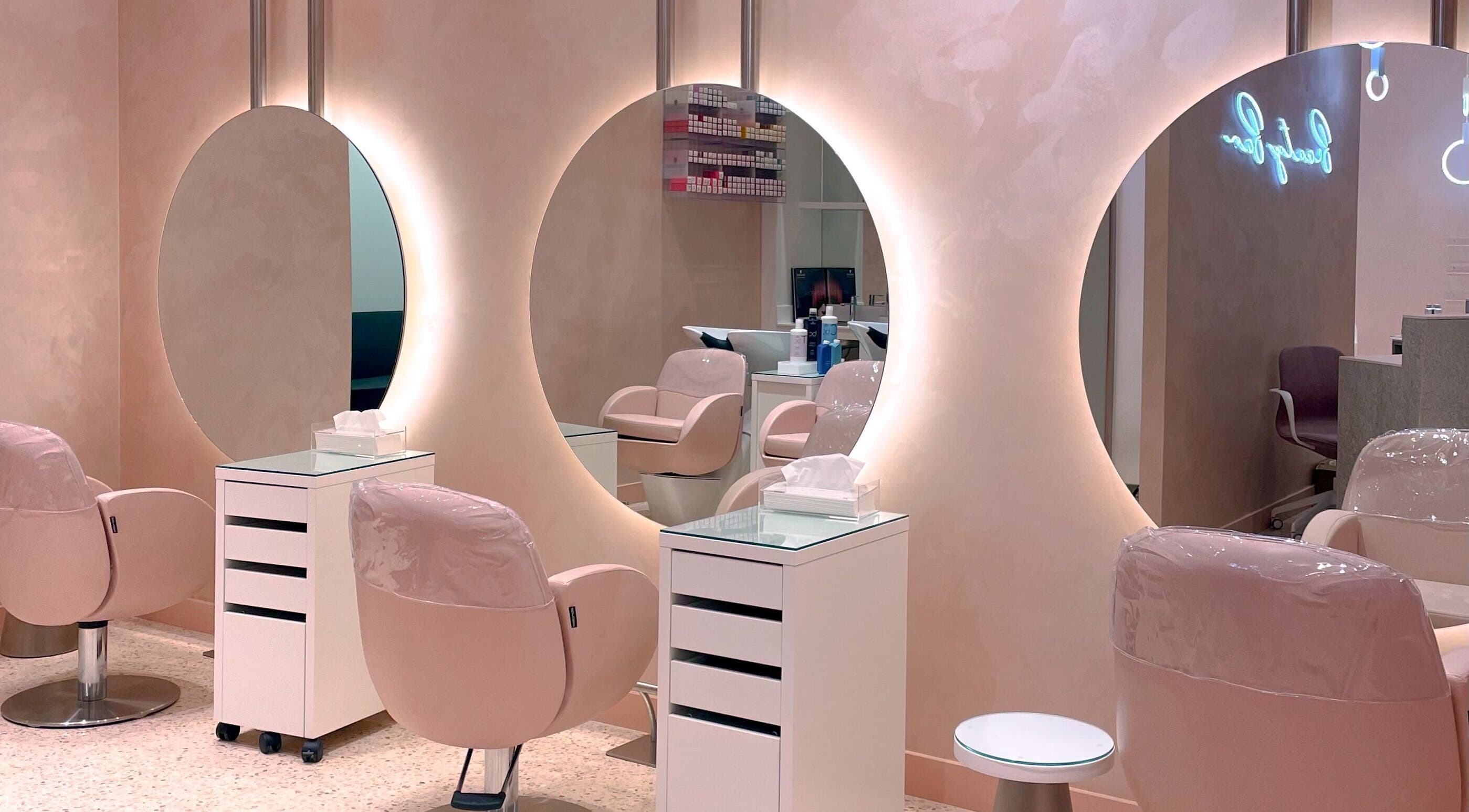 Chic interior of VO2 Beauty Bar in Doha, Doha, QA with elegant pink chairs and illuminated mirrors.