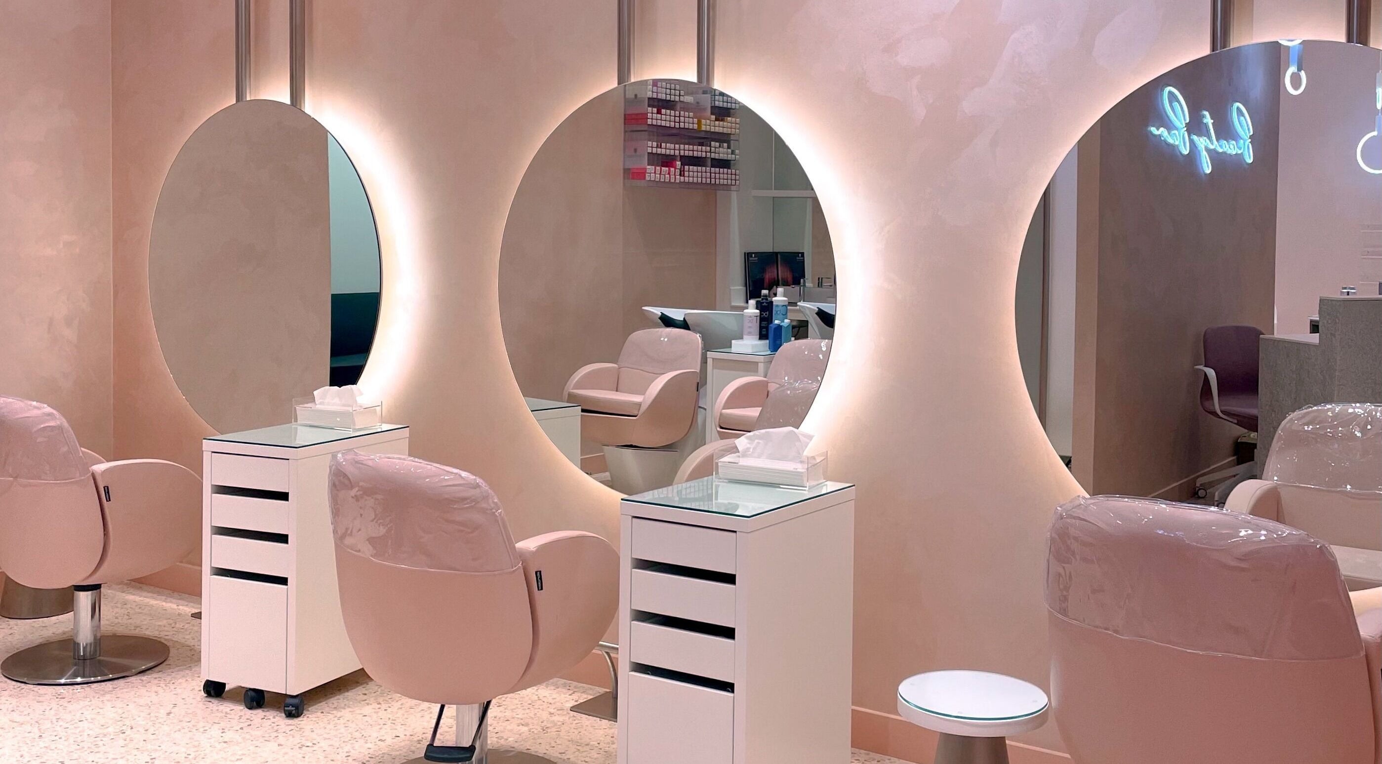 Chic interior of VO2 Beauty Bar in Doha, Doha, QA with elegant pink chairs and illuminated mirrors.