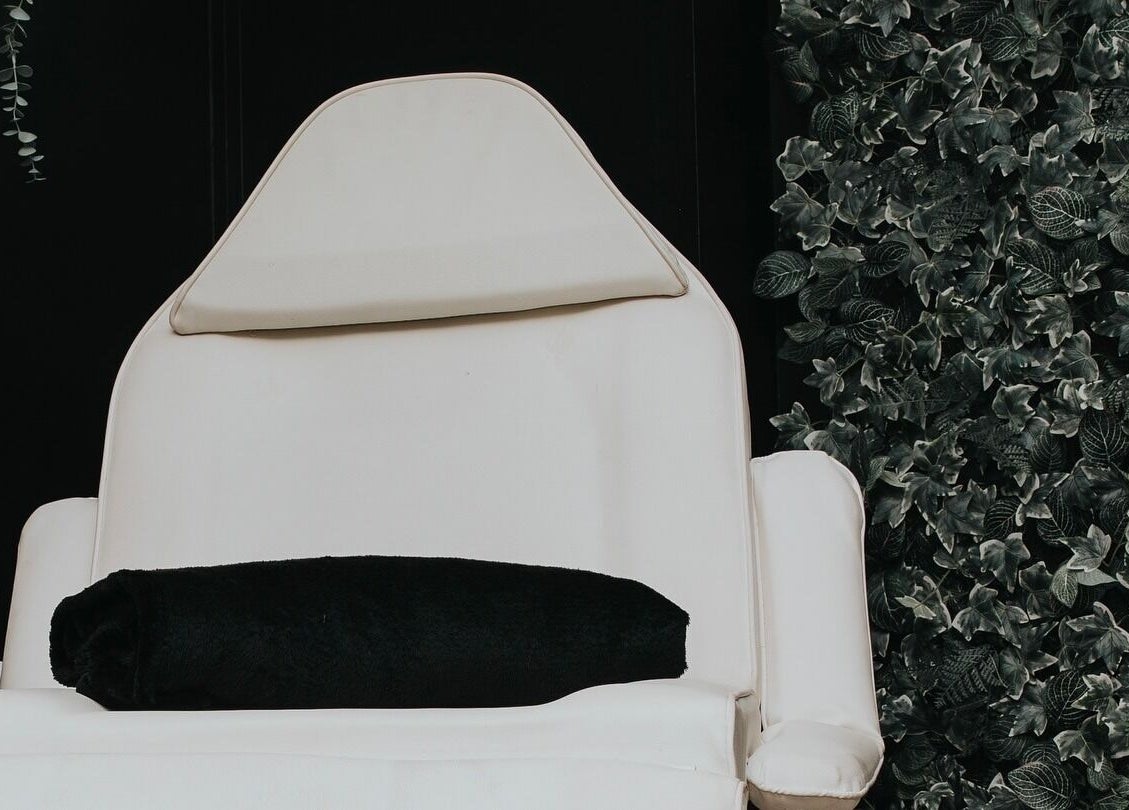 Luxury treatment chair at The Glow Up Clinic, Fareham, England, GB with lush greenery backdrop.