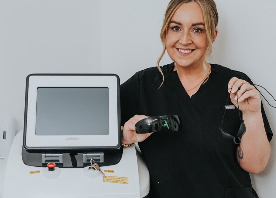 Smiling professional holding laser equipment at The Glow Up Clinic, Fareham, England, GB.