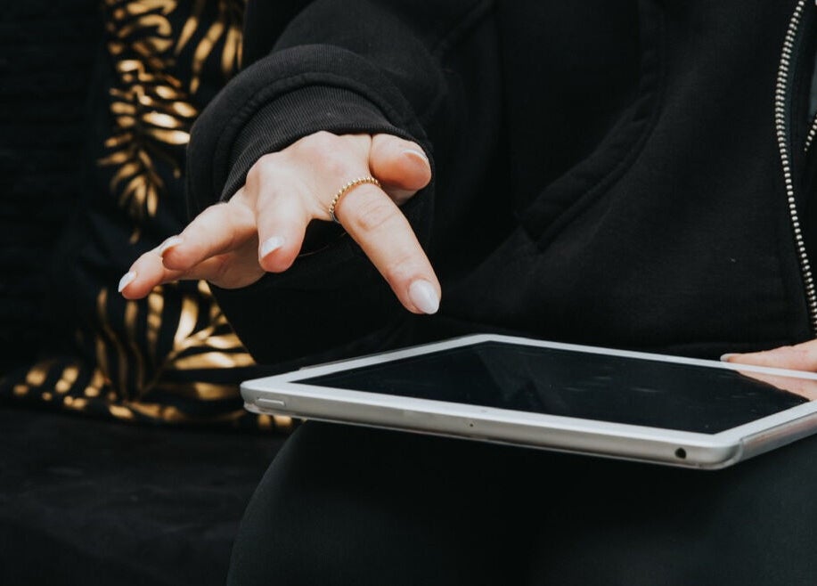 A hand poised over a tablet at The Glow Up Clinic, Fareham, England, GB, highlighting modern technology in beauty.