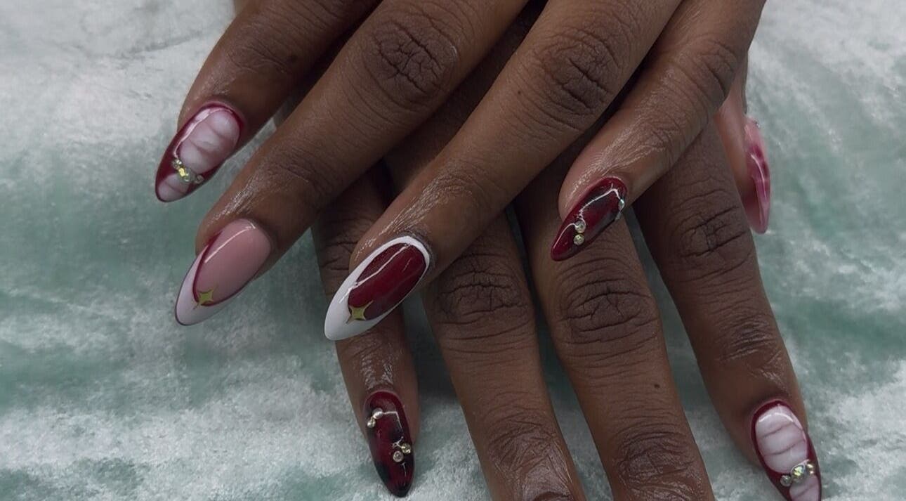 Intricate burgundy and pearl nail art at iCandy, Rodney Bay, Gros Islet, LC, showcasing elegant hand design.