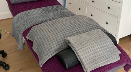Massage bed at The Relaxation Room Leixlip, Leixlip, County Kildare, IE with soft gray and purple linens.