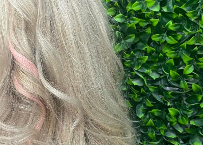 Blonde hair with curls at Polaris Hair Salon Raceview in Raceview, Queensland, AU against a green leafy backdrop.