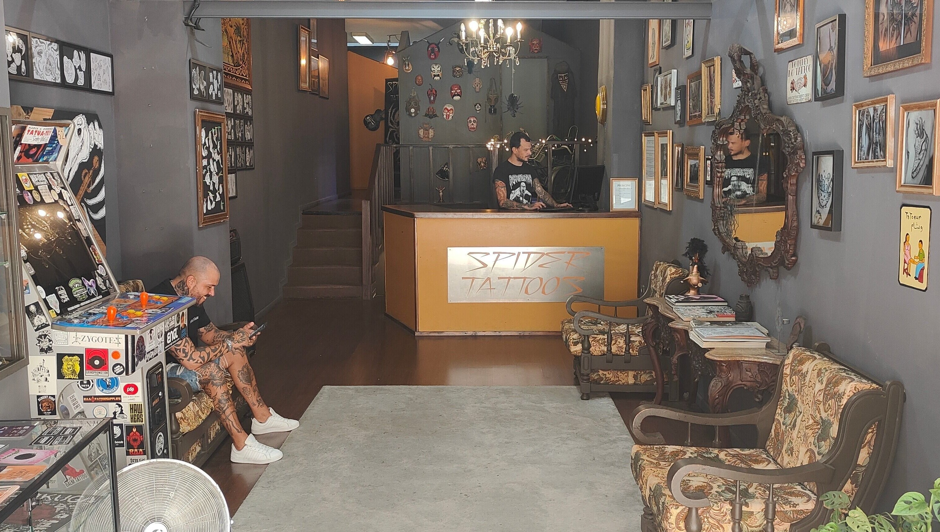 Interior acolhedor da SPIDER TATTOOS em Porto, Porto, PT, com obras e móveis vintage.