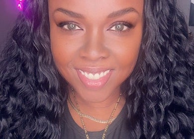 Friendly stylist at Passion Hair Solutions in Lanham, Maryland, US with wavy hair and welcoming smile.