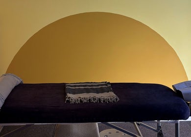 Comfortable massage table at Shep Sports Massage, London, England, GB, against a calming yellow backdrop.