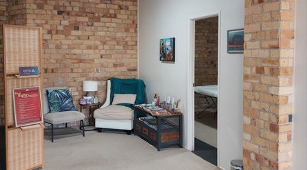 Relaxing seating area at Prime Massage Therapy (Onehunga), Auckland, NZ with brick walls and a massage room.