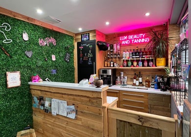 Chic reception at LUX Beauty and Tanning LTD in Leabrooks, England. Inviting green wall and neon lights.