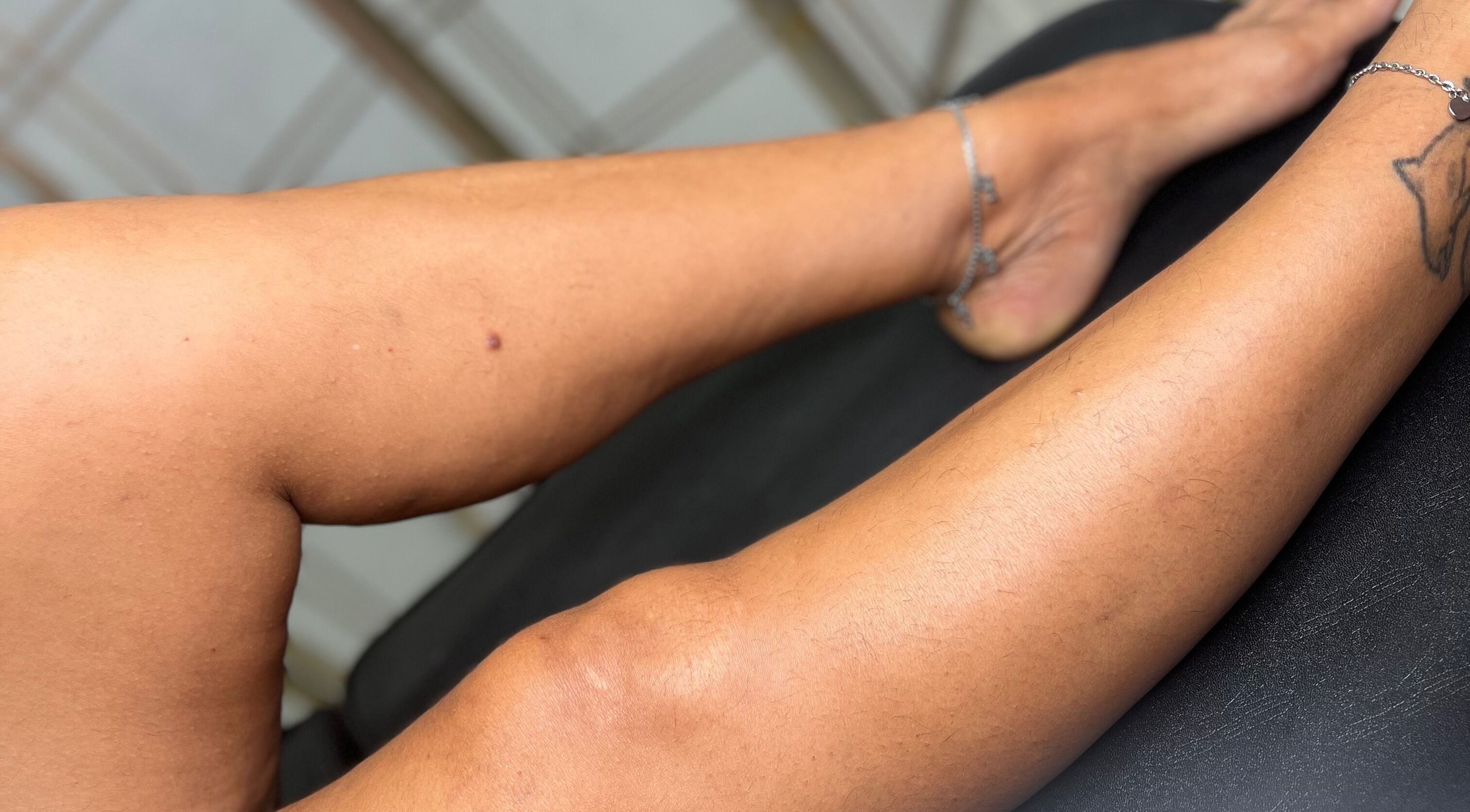 Close-up of tattooed leg on a black surface at Ethereal Beauty, Willemstad, Curaçao, CW.