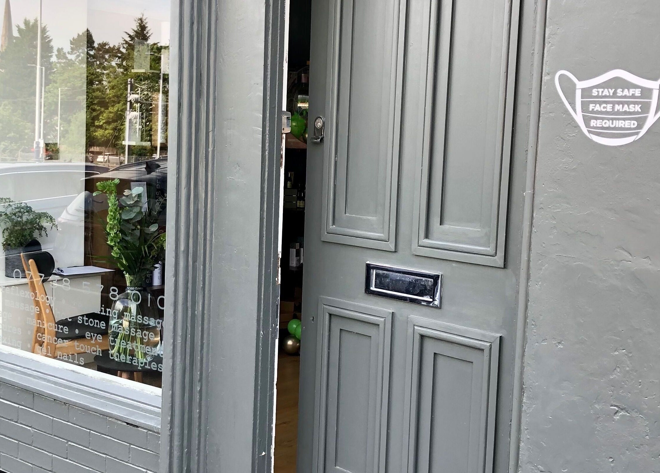 Charming entrance of Sans Peur Therapies in Lenzie, Scotland, GB, featuring a green door and window with plants.