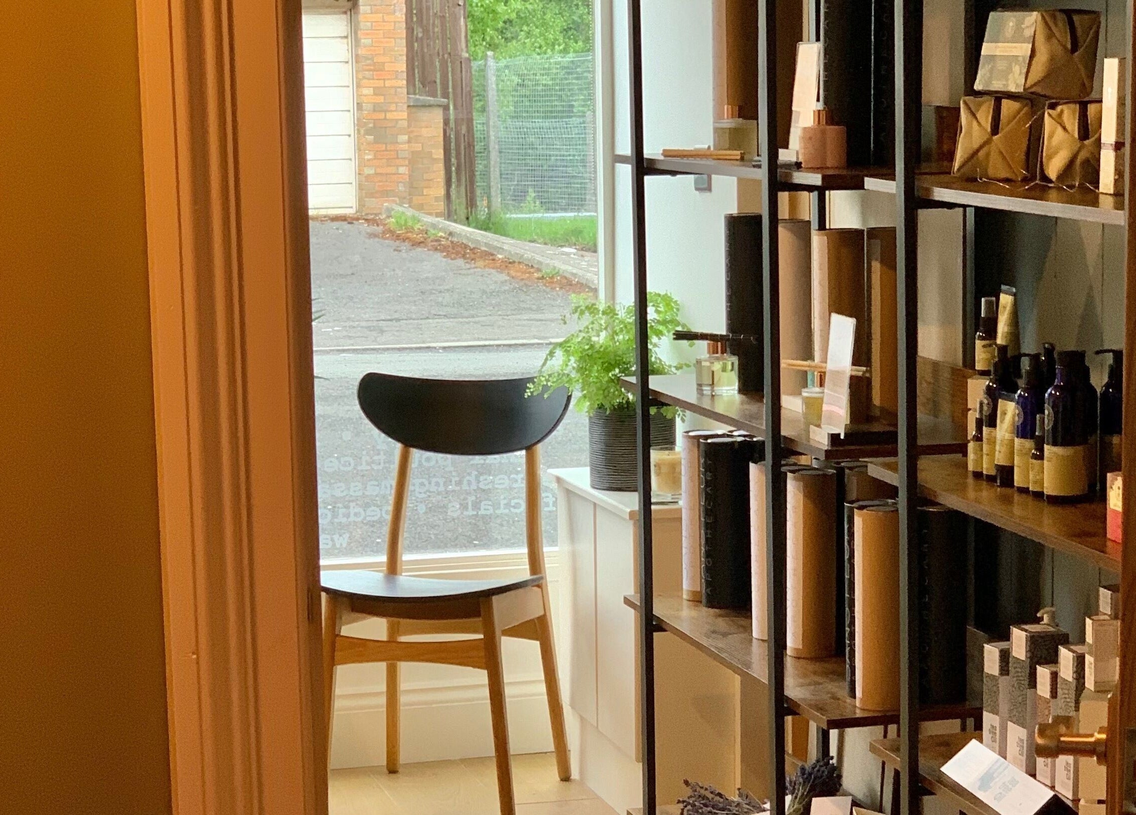 Cozy reading nook at Sans Peur Therapies, Lenzie, Scotland, GB. Natural light and wellness products on shelves.
