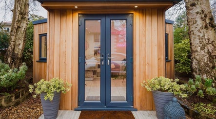 Modern wooden entrance of The Beauty Shack in Failand, England, GB, surrounded by green plants.