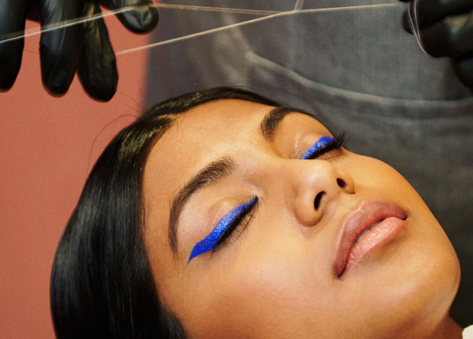 Eyebrow threading at Iris Avenue, London, England, GB with vibrant blue eyeliner accent on woman.