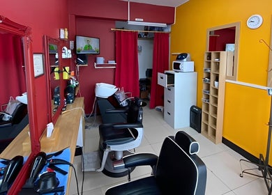 Stylish interior of Soorya Barbers in Harrow, England, GB with modern chairs and vibrant decor.