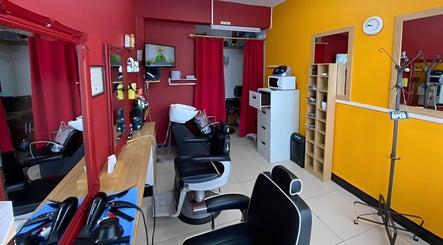 Stylish interior of Soorya Barbers in Harrow, England, GB with modern chairs and vibrant decor.