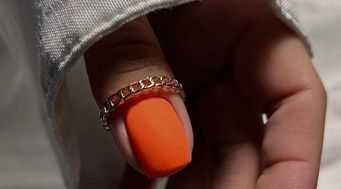 Close-up of a stylish orange nail with a gold ring, crafted at Saidi Nails, Limassol, Limassol, CY.