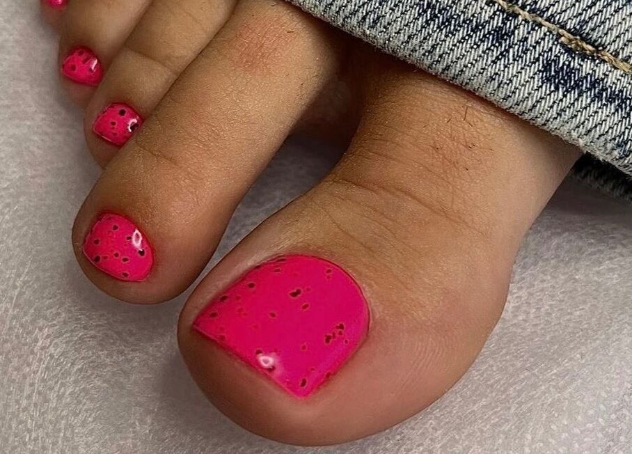 Bright pink toenails with black specks designed at Saidi Nails, Limassol, Limassol, CY.