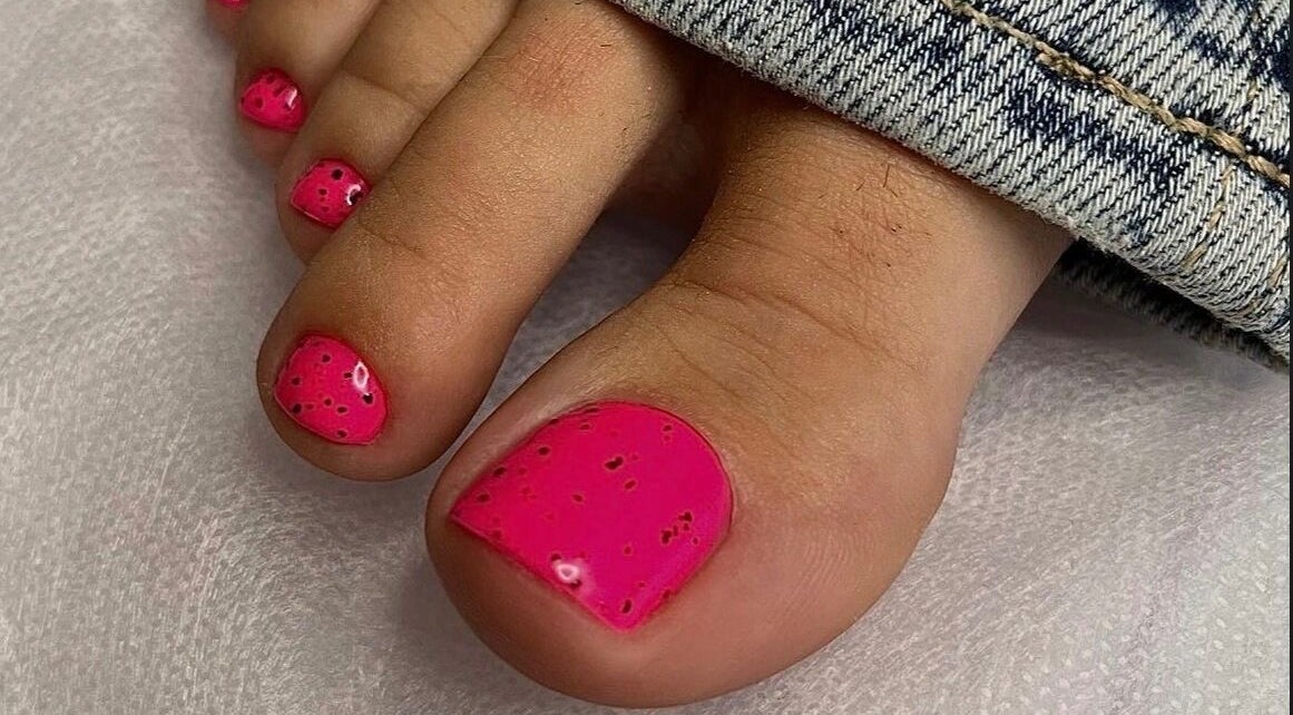 Bright pink toenails with black specks designed at Saidi Nails, Limassol, Limassol, CY.