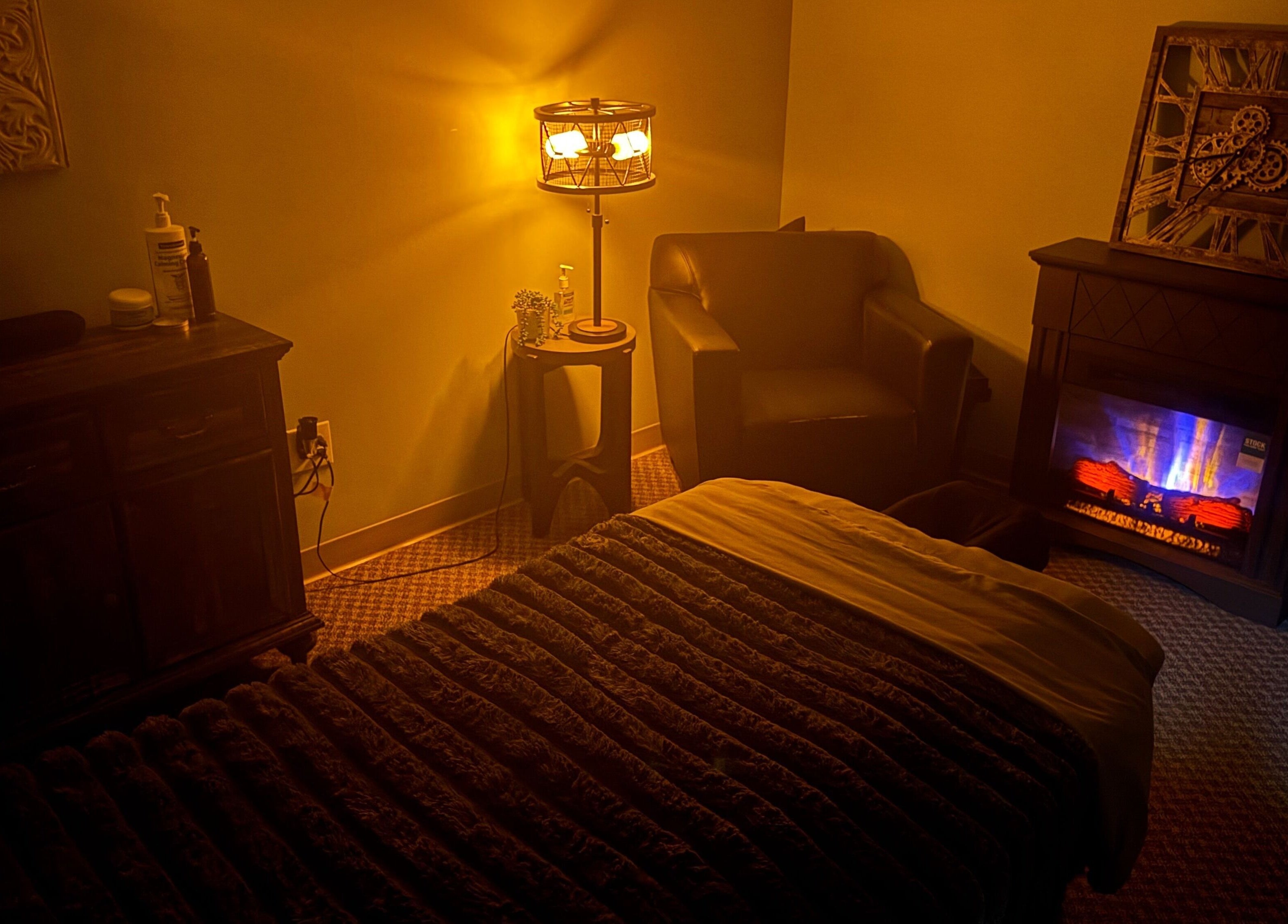 Warm massage room at Manna Medical Massage, Burton, Michigan, US, with ambient lighting and a cozy chair.