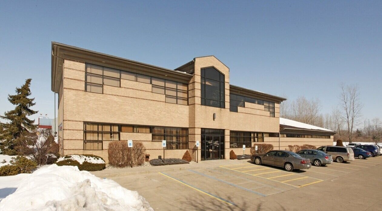 Exterior of Manna Medical Massage in Burton, Michigan, US, showcasing modern architecture and ample parking.