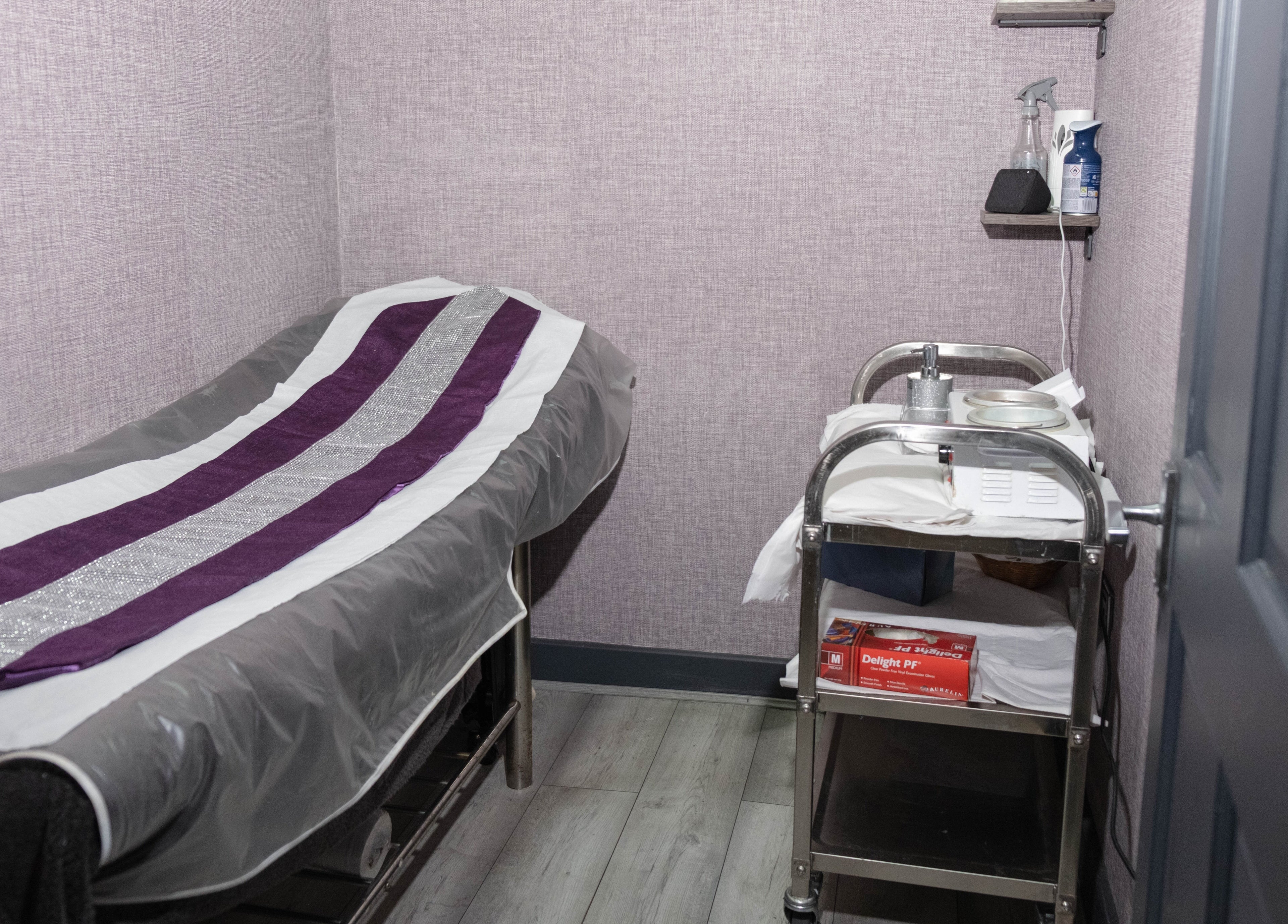 Cozy treatment room at Riddhis Beauty Clinic, London, England, GB with a massage table and service cart.