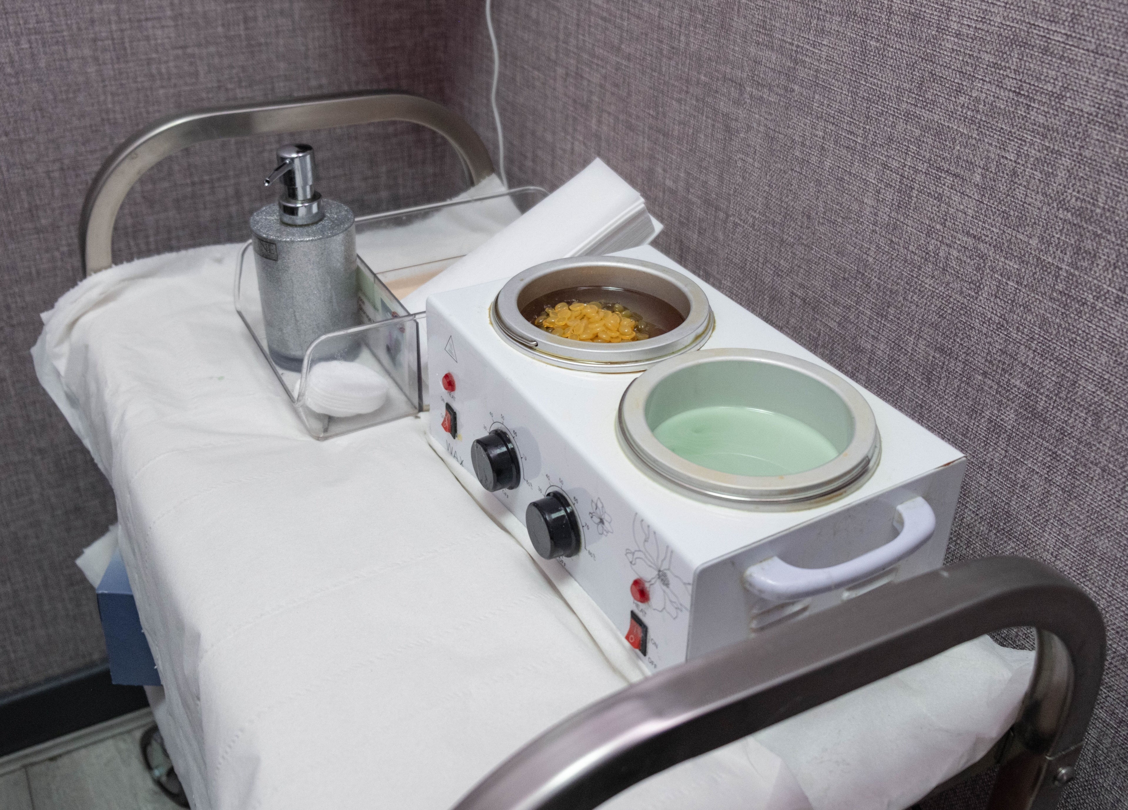 Wax station at Riddhis Beauty Clinic, London, England, GB, showcasing wax pots and dispenser.