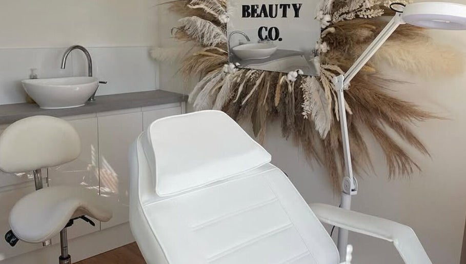 Spa treatment room at Sisters Beauty Co., Costock, England, featuring a chic white chair and decor.