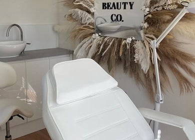 Spa treatment room at Sisters Beauty Co., Costock, England, featuring a chic white chair and decor.