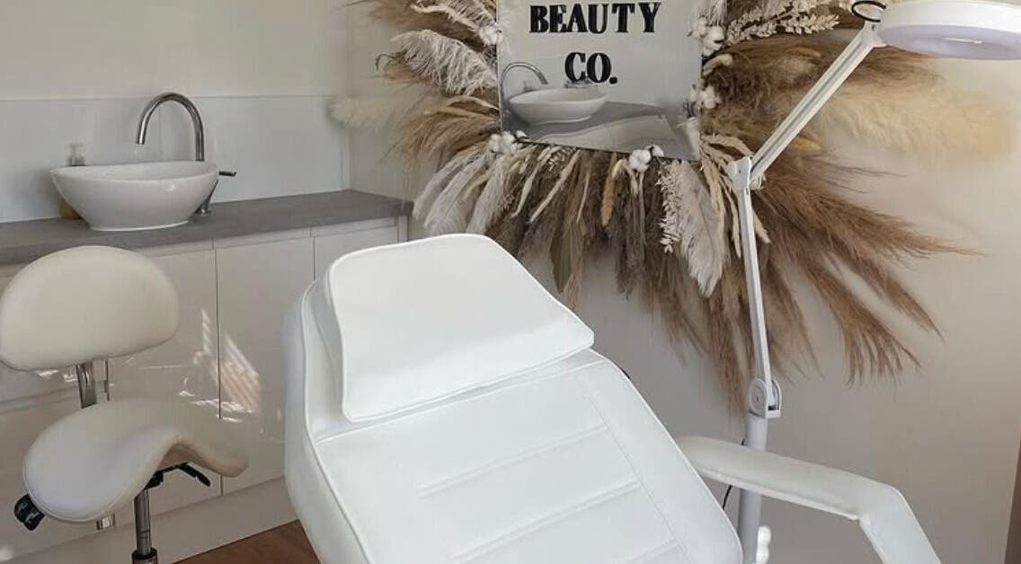 Spa treatment room at Sisters Beauty Co., Costock, England, featuring a chic white chair and decor.