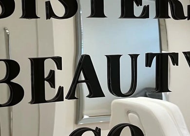 Sleek mirrored wall with 'Sisters Beauty Co.' logo in Costock, England, GB. Modern decor accents beauty.