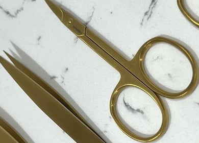 Elegant golden scissors and tweezers at Sisters Beauty Co., Costock, England, GB, showcasing top-notch beauty tools.