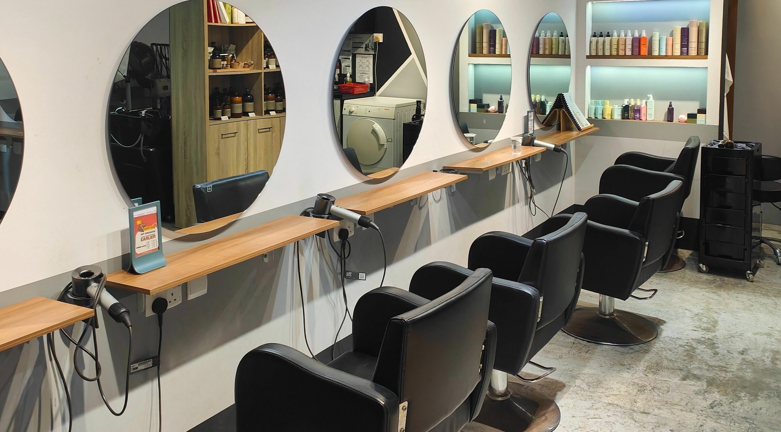 Elegant salon setup at Hair by Common Studio - Queenstown, Singapore, SG featuring stylish mirrors and chairs.