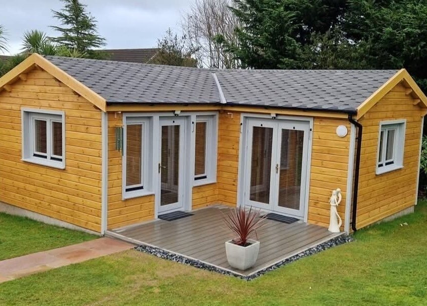 Charming wooden cabin at Body & Mind by Hannah in Douglas, Douglas, IM, surrounded by lush greenery.