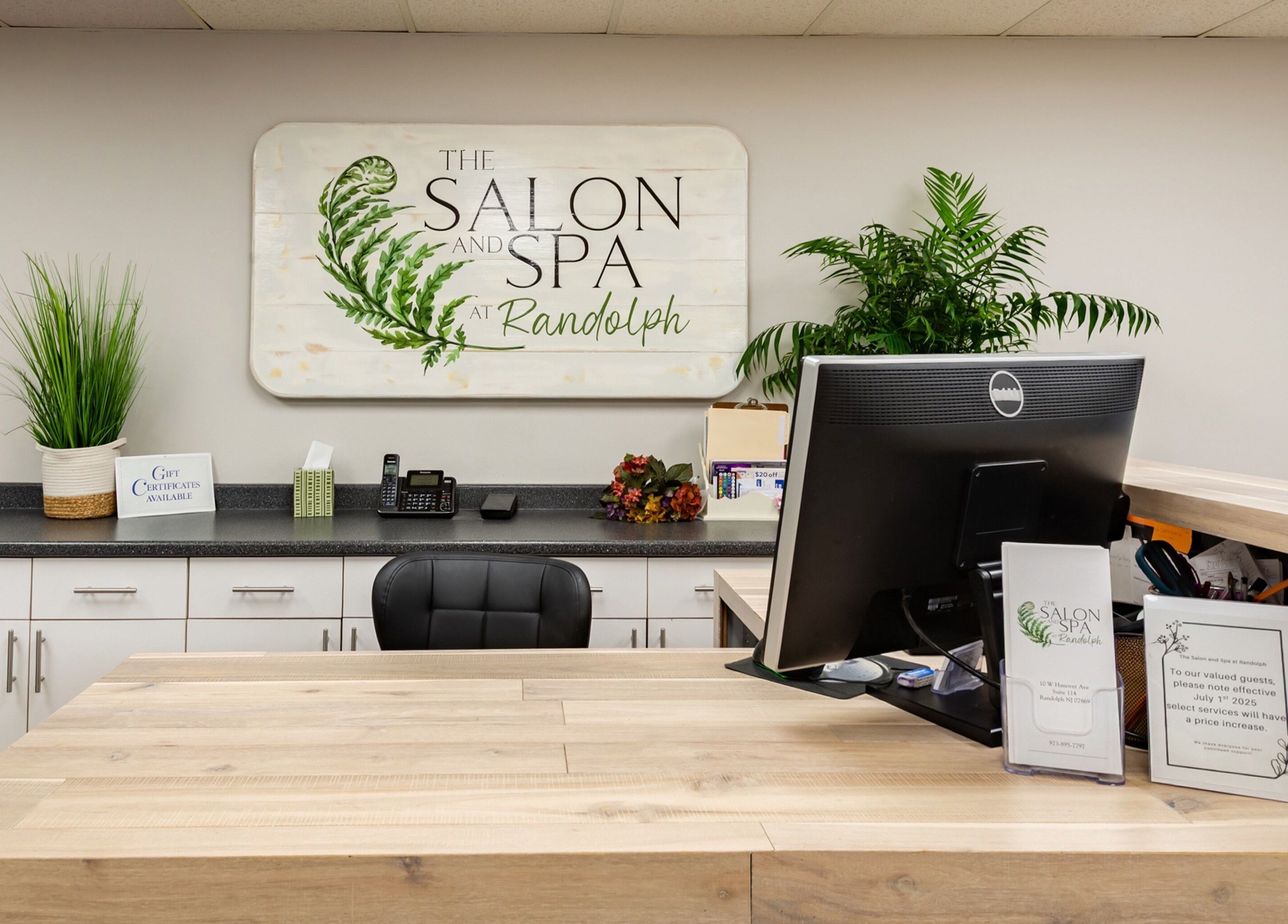 Reception area at The Salon and Spa at Randolph LLC, Randolph, New Jersey, US, featuring greenery and signage.