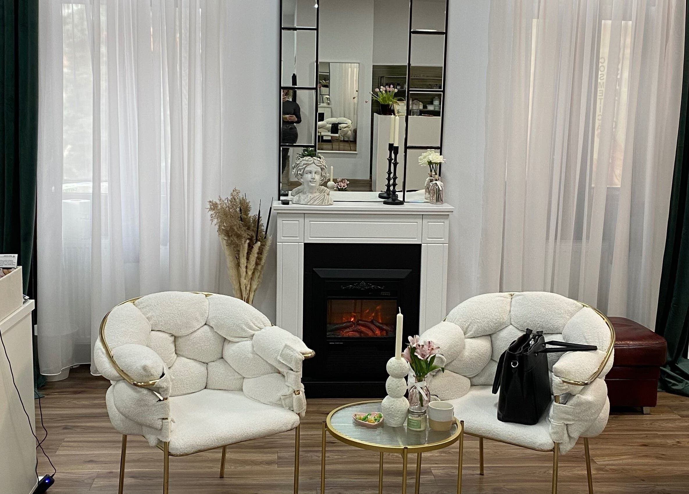 Lounge stilat la Infinity Beauty Salon, Târgu Mureș, Județul Mureș, RO, cu fotolii albe și șemineu.