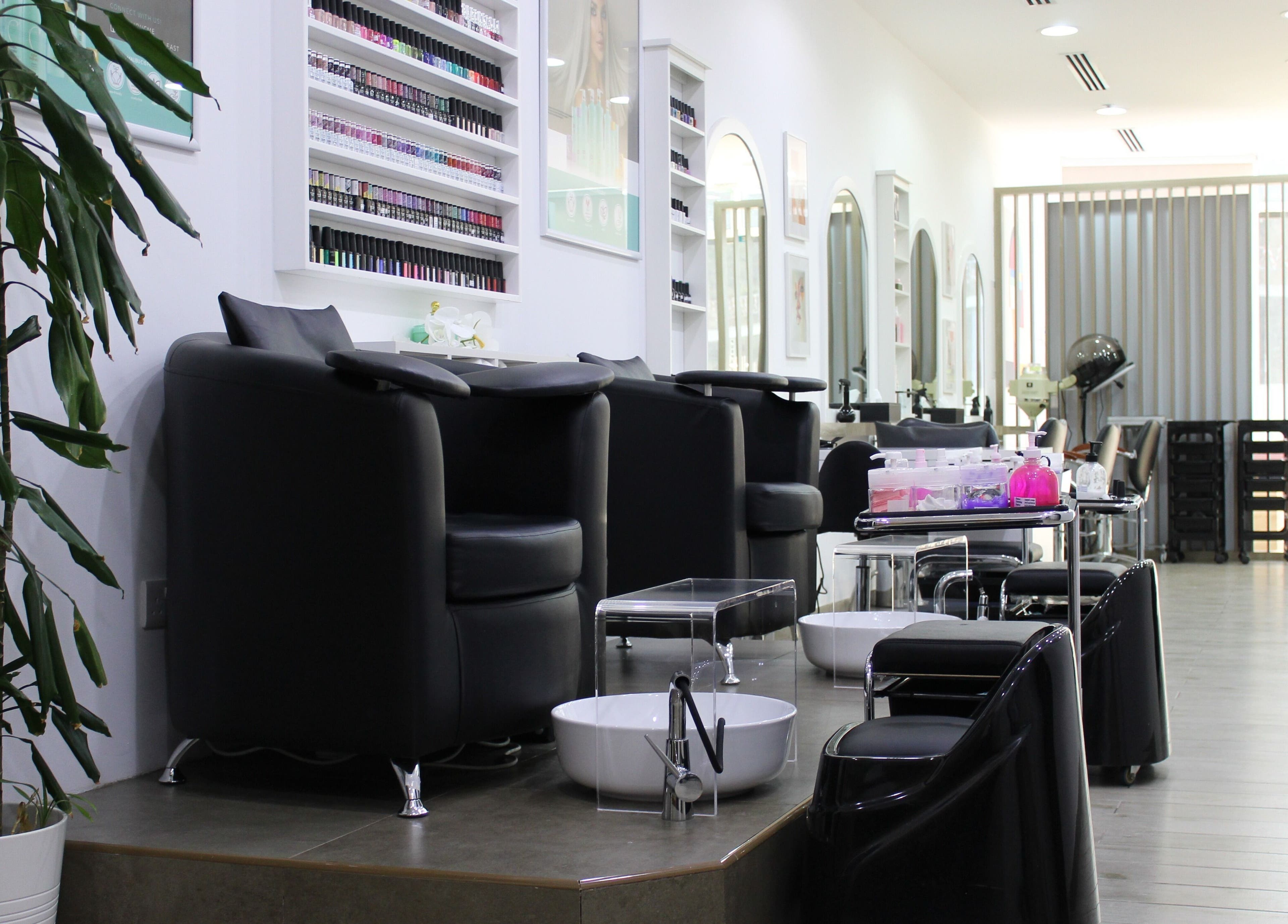 Elegant interior of Salon Script in Dubai, AE, showcasing nail stations and modern seating under soft lighting.