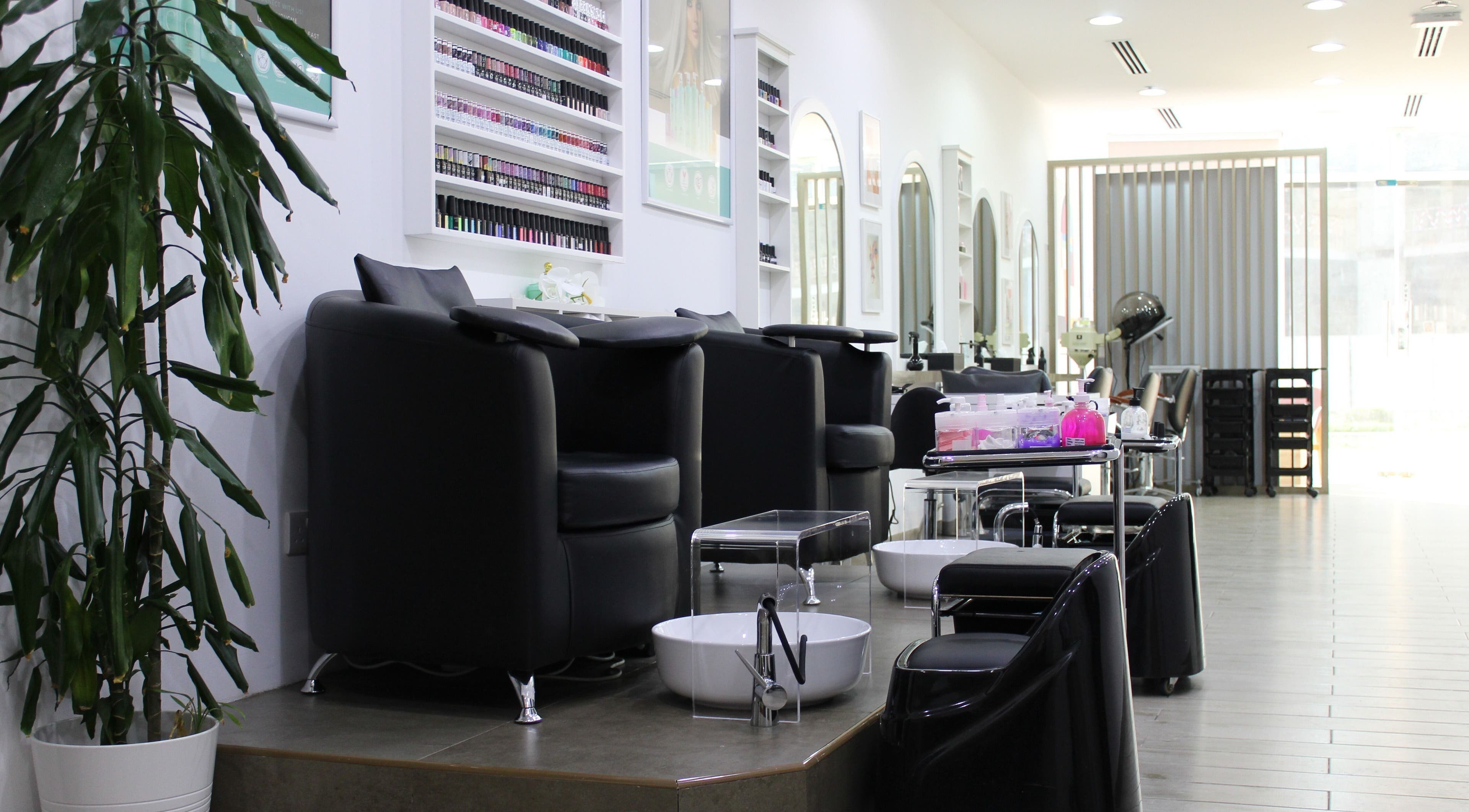 Elegant interior of Salon Script in Dubai, AE, showcasing nail stations and modern seating under soft lighting.
