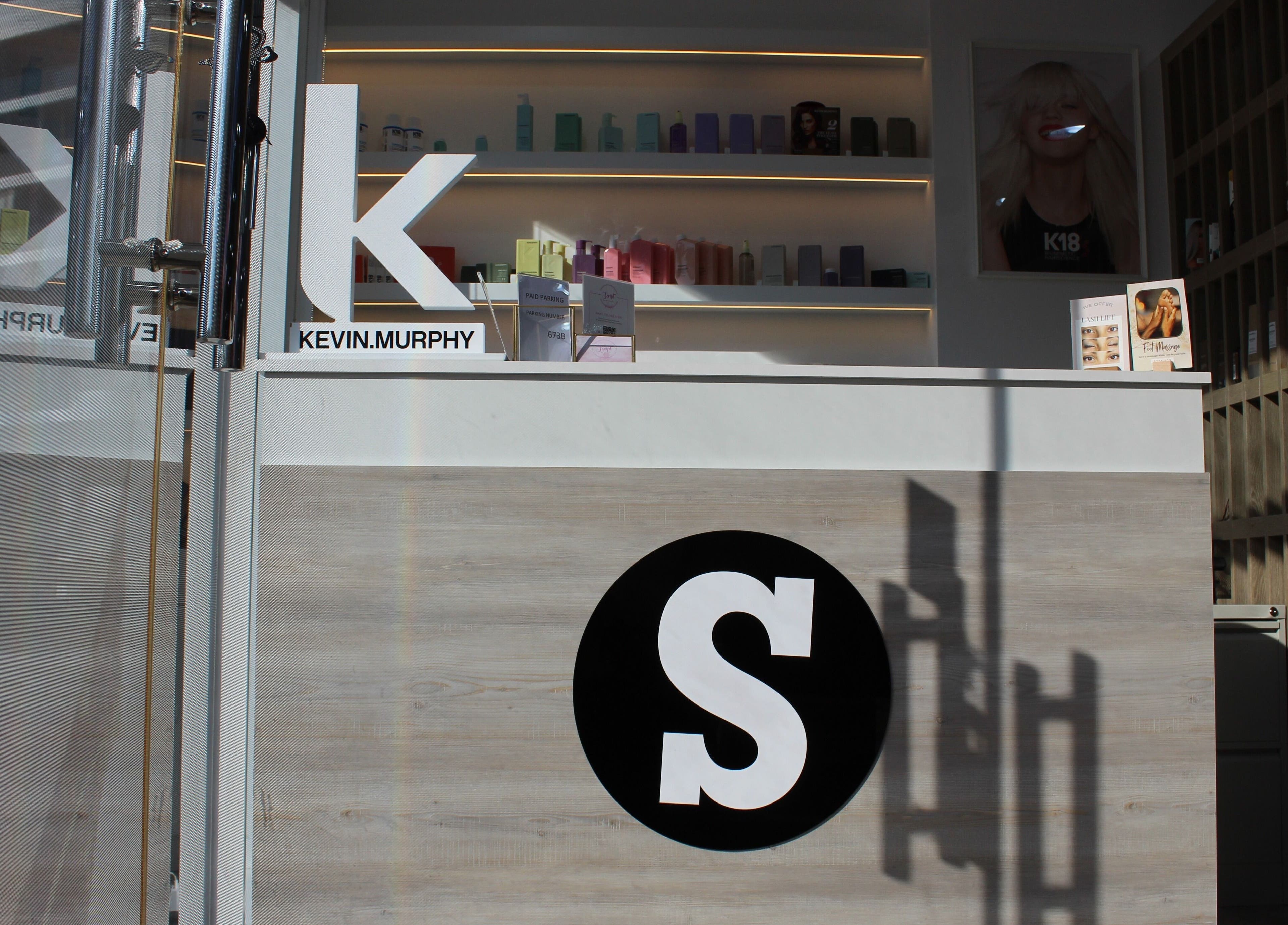 Reception area of Salon Script, Dubai, AE with elegant shelving and branded displays.