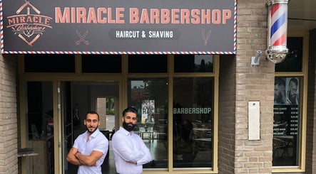 Twee mannen staan voor Miracle Barbershop Maarssen, Utrecht, NL onder het winkelbord.