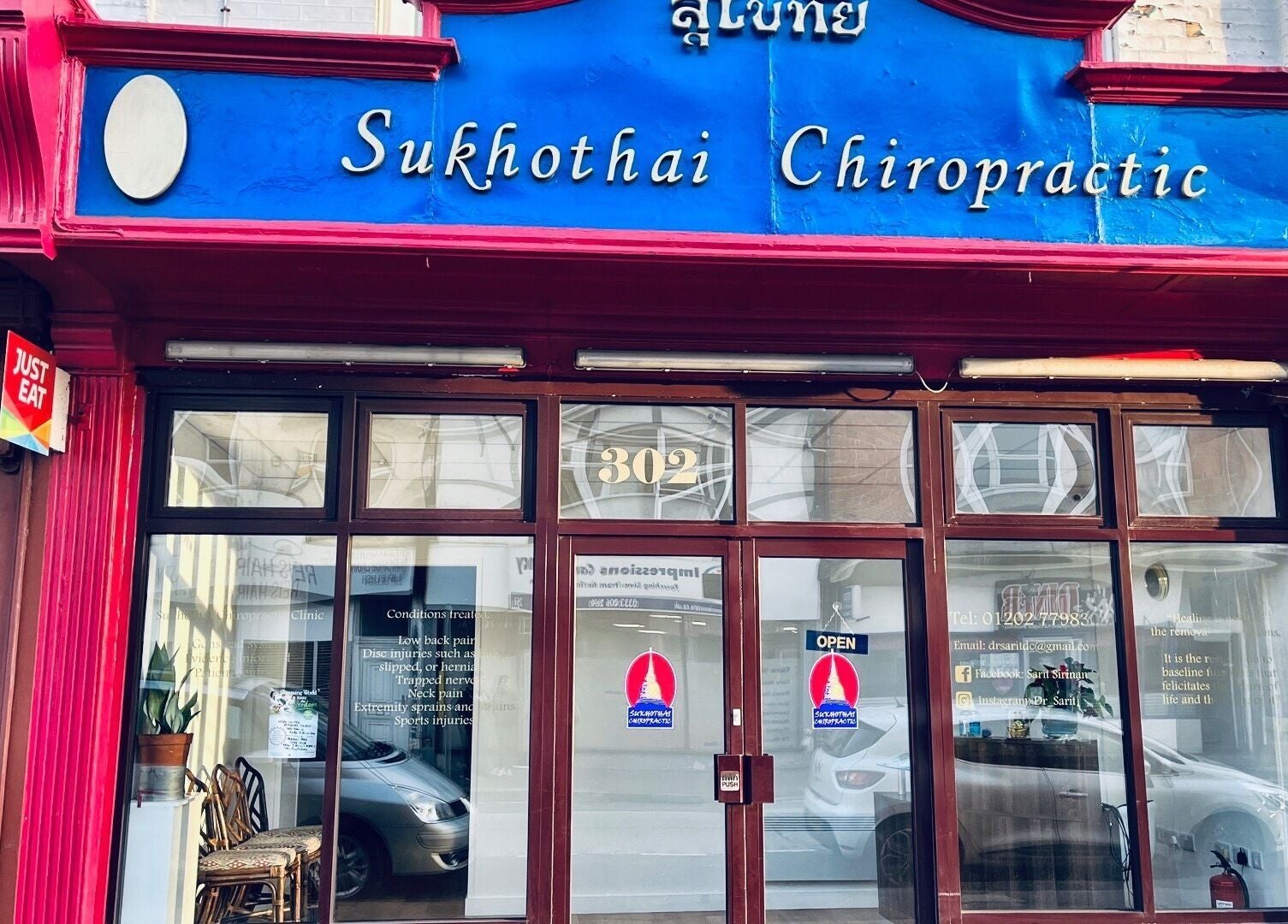 Exterior of Sukhothai Chiropractic Clinic in Bournemouth, England, GB with red facade and blue sign.