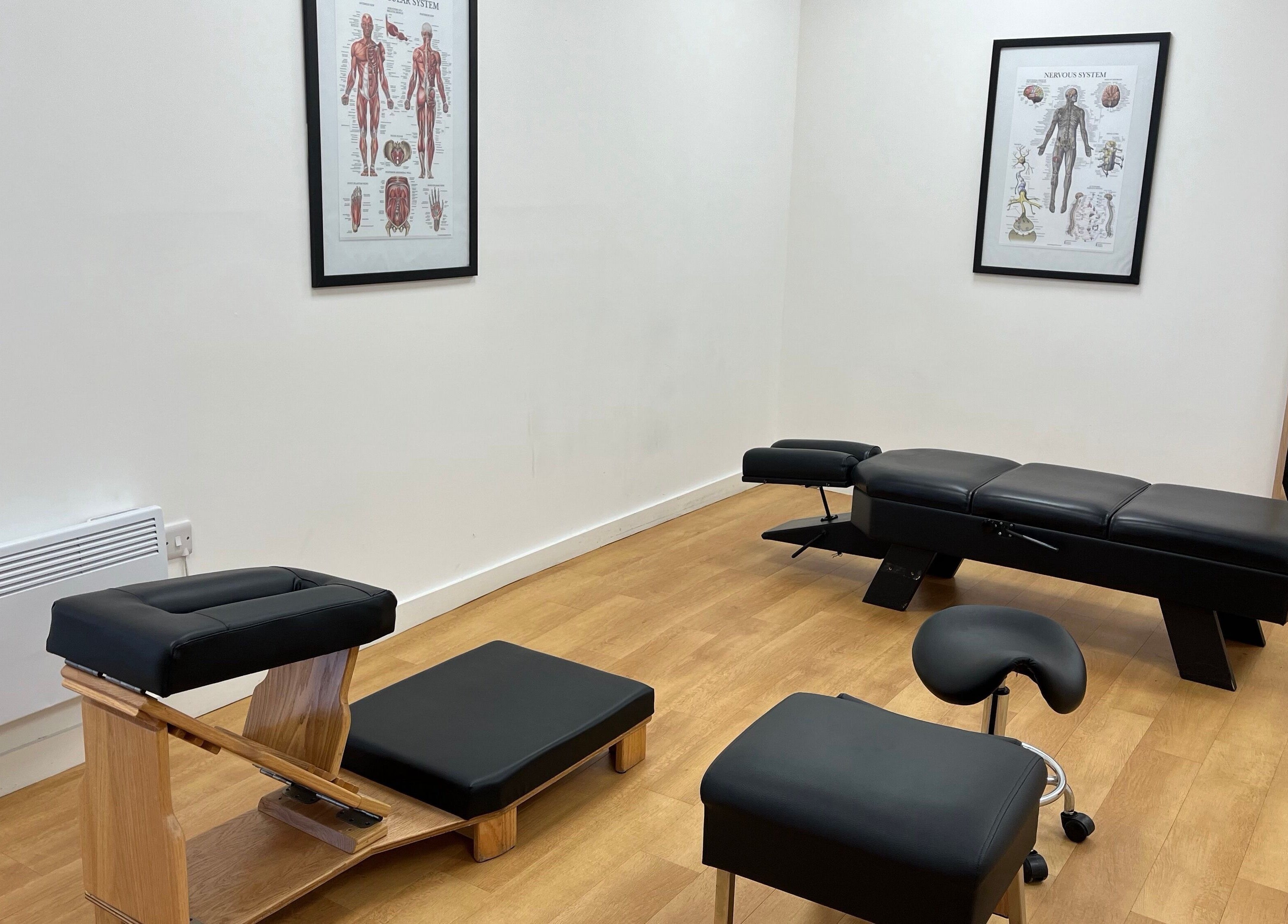 Chiropractic treatment room at Sukhothai Chiropractic Clinic, Bournemouth, England, GB showing exam tables and anatomy charts.
