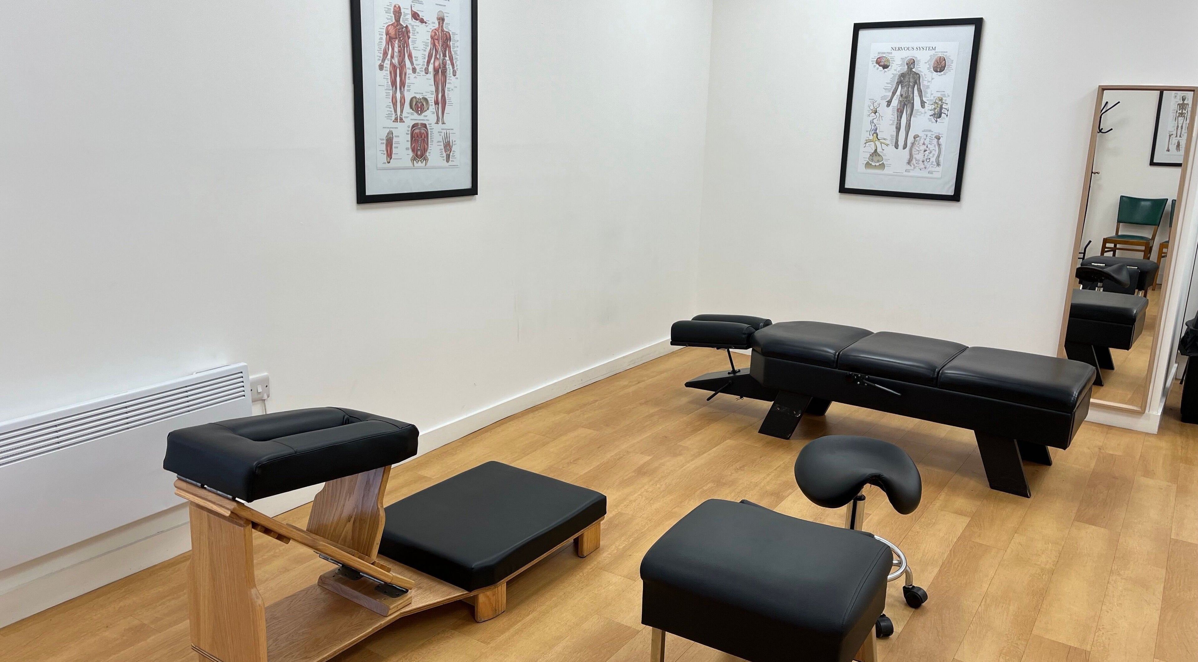 Chiropractic treatment room at Sukhothai Chiropractic Clinic, Bournemouth, England, GB showing exam tables and anatomy charts.