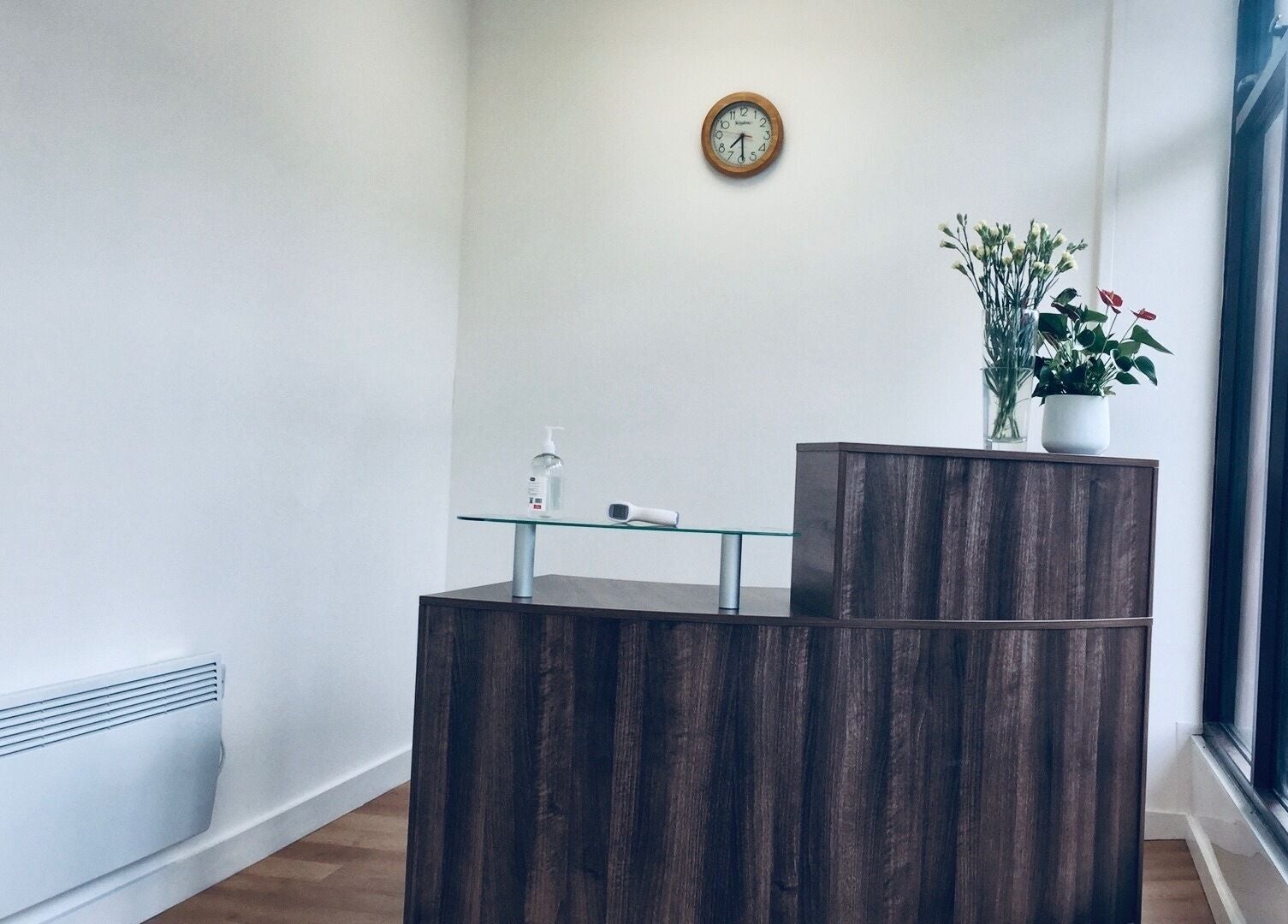 Reception area at Sukhothai Chiropractic Clinic, Bournemouth, England, GB with wooden desk and floral decor.