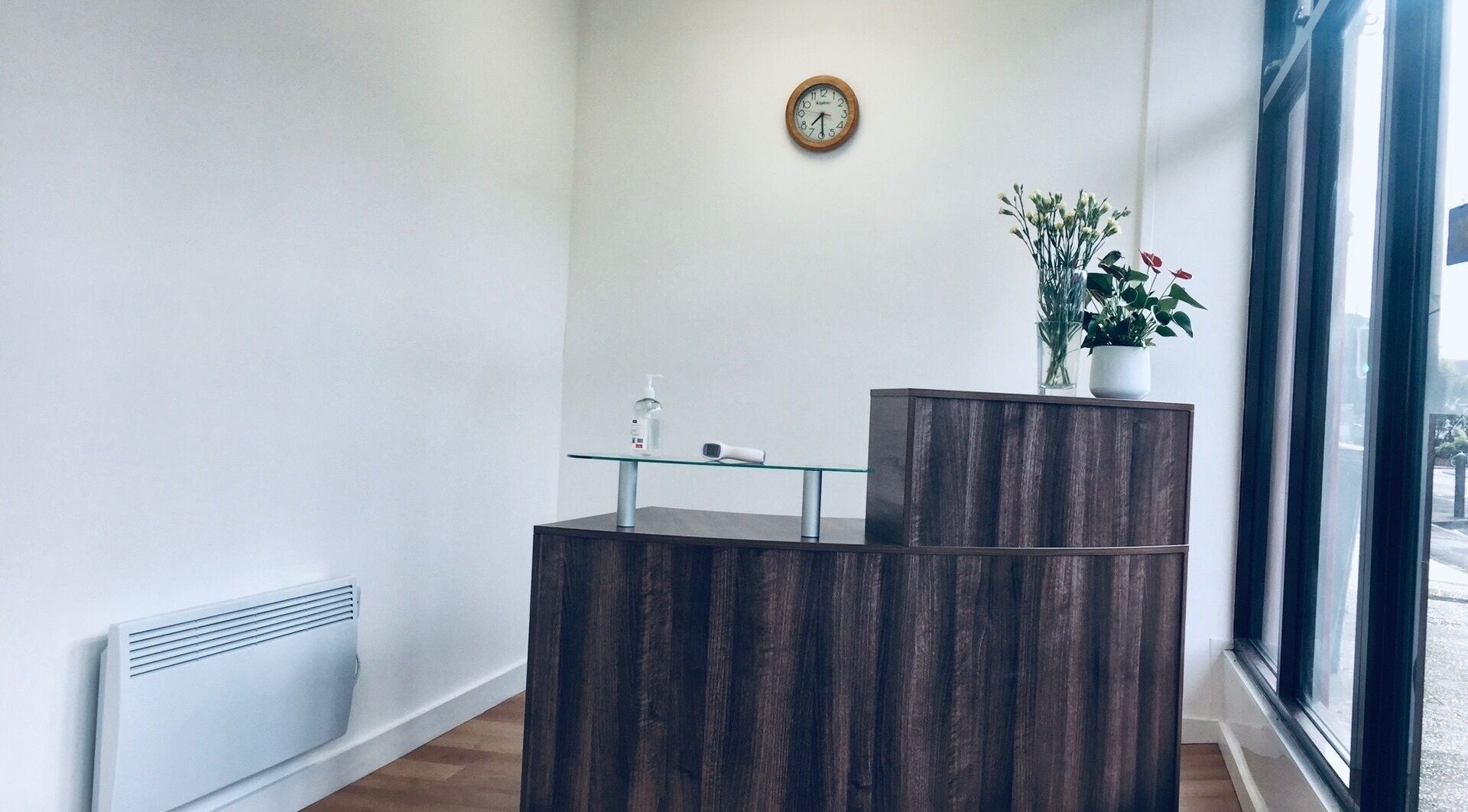 Reception area at Sukhothai Chiropractic Clinic, Bournemouth, England, GB with wooden desk and floral decor.