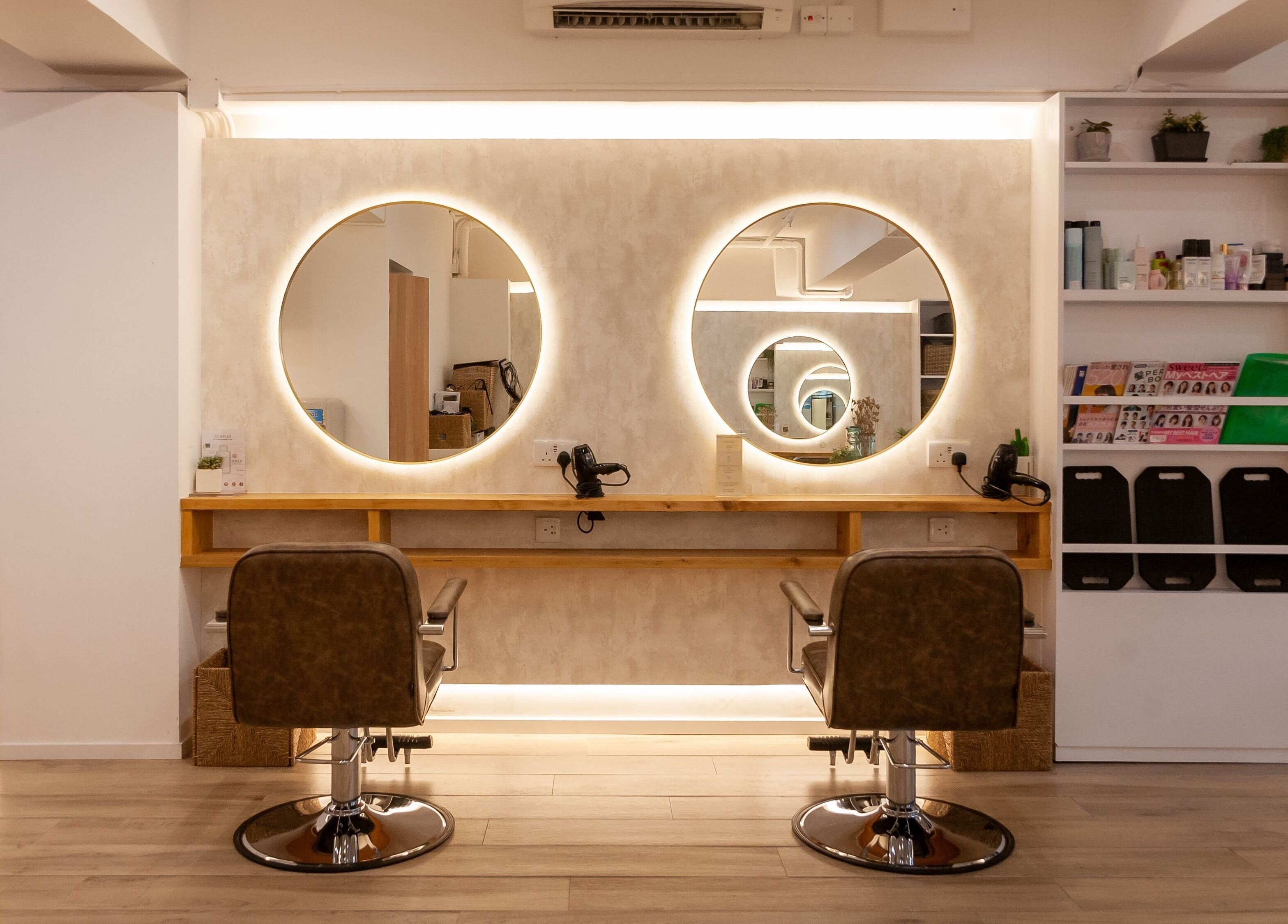 Elegant hairstyling station at Sozo Hair Design, Hong Kong Island, HK, with illuminated round mirrors.