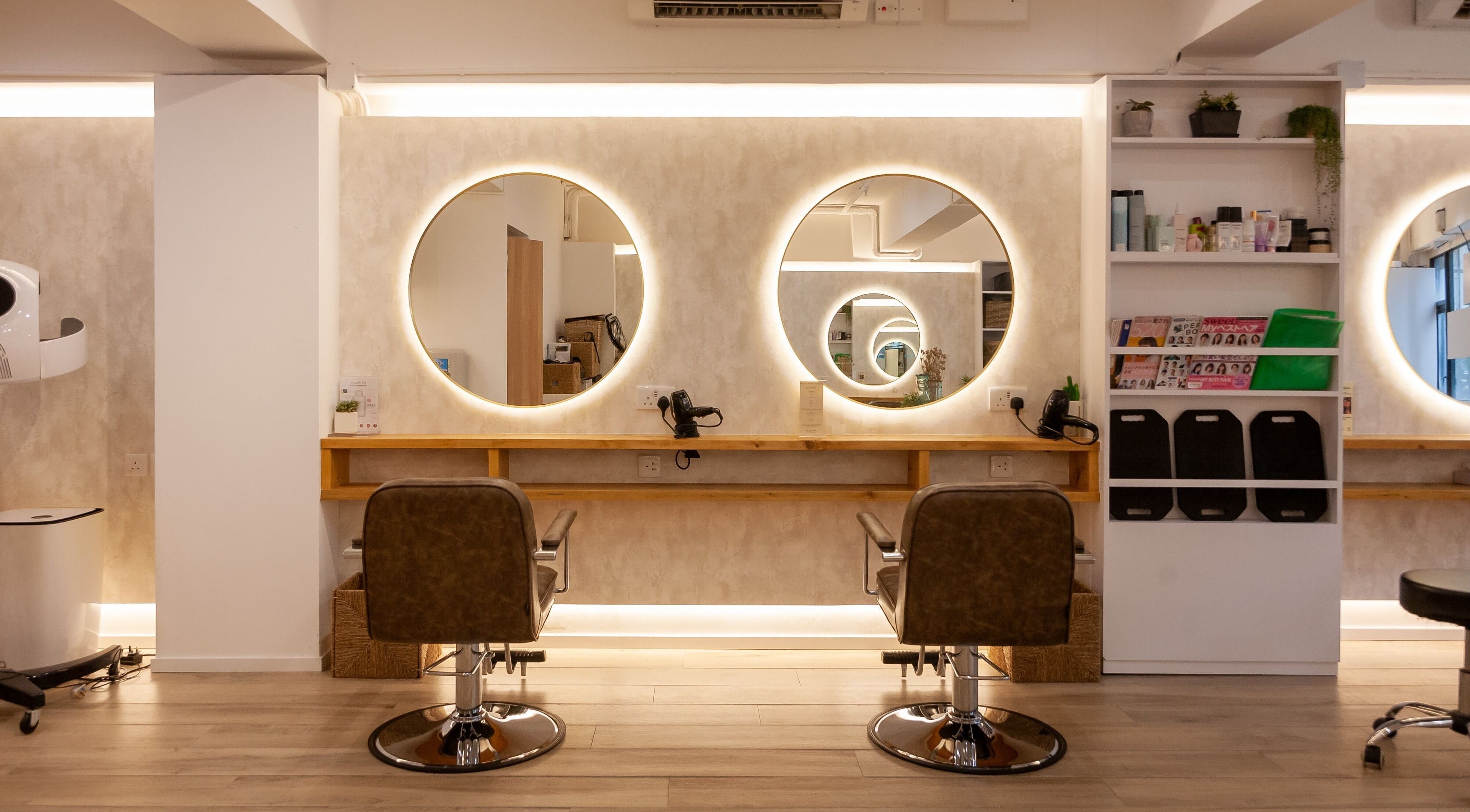 Elegant hairstyling station at Sozo Hair Design, Hong Kong Island, HK, with illuminated round mirrors.