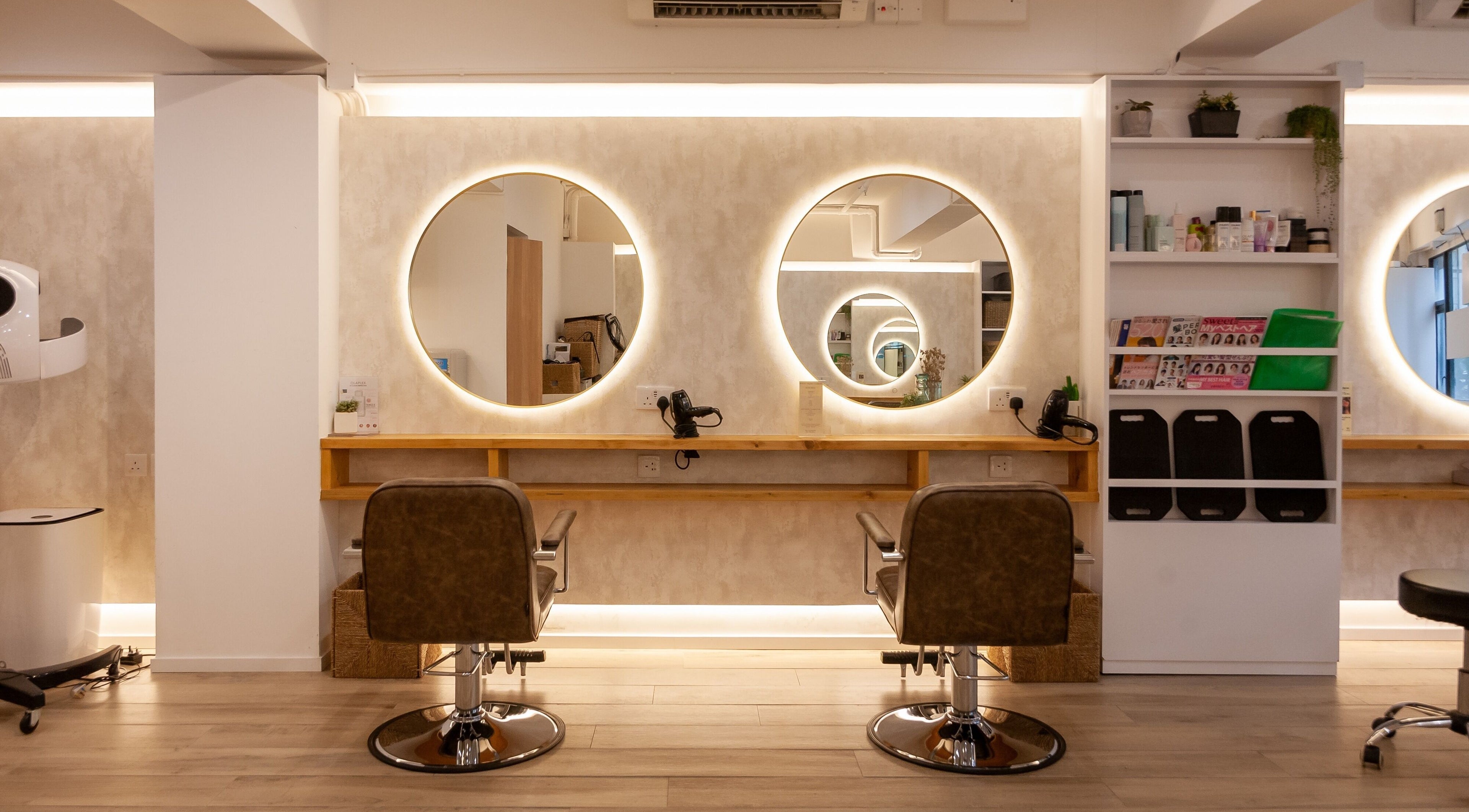 Elegant hairstyling station at Sozo Hair Design, Hong Kong Island, HK, with illuminated round mirrors.