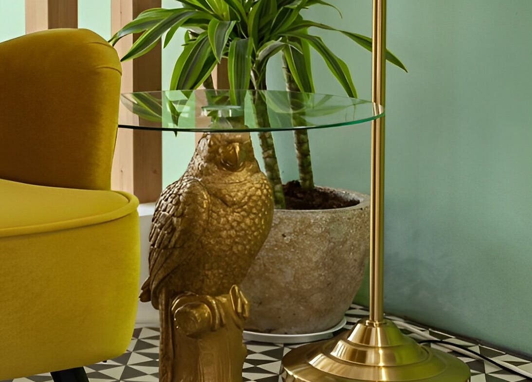 Chic corner at Pink Ivy, Στρόβολος, Λευκωσία, CY with a golden owl table beside a yellow chair and potted plant.